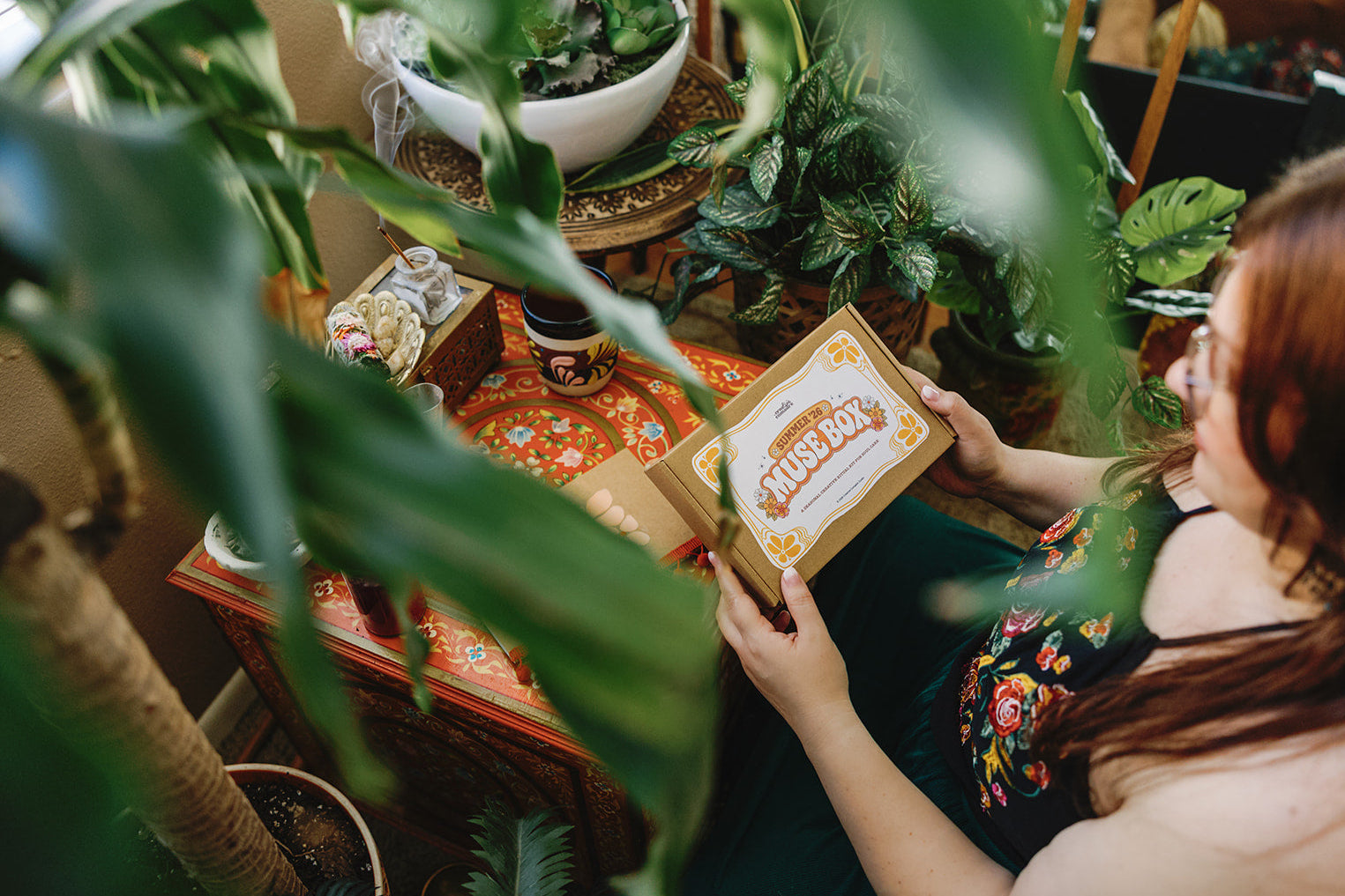 Person holding a box labeled 'Plants Box' surrounded by greenery